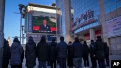 La gente mira una transmisión en vivo del servicio conmemorativo del difunto expresidente chino Jiang Zemin, donde el presidente chino, Xi Jinping, pronuncia un discurso en la pantalla en la calle comercial Wangfujing en Beijing, el martes 6 de diciembre de 2022.