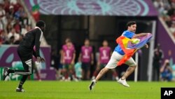 A protester runs across the field with a rainbow flag during the World Cup soccer match between Portugal and Uruguay at Lusail Stadium in Lusail, Qatar, Nov. 28, 2022. 