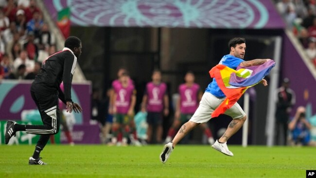 A protester runs across the field with a rainbow flag during the World Cup soccer match between Portugal and Uruguay at Lusail Stadium in Lusail, Qatar, Nov. 28, 2022.
