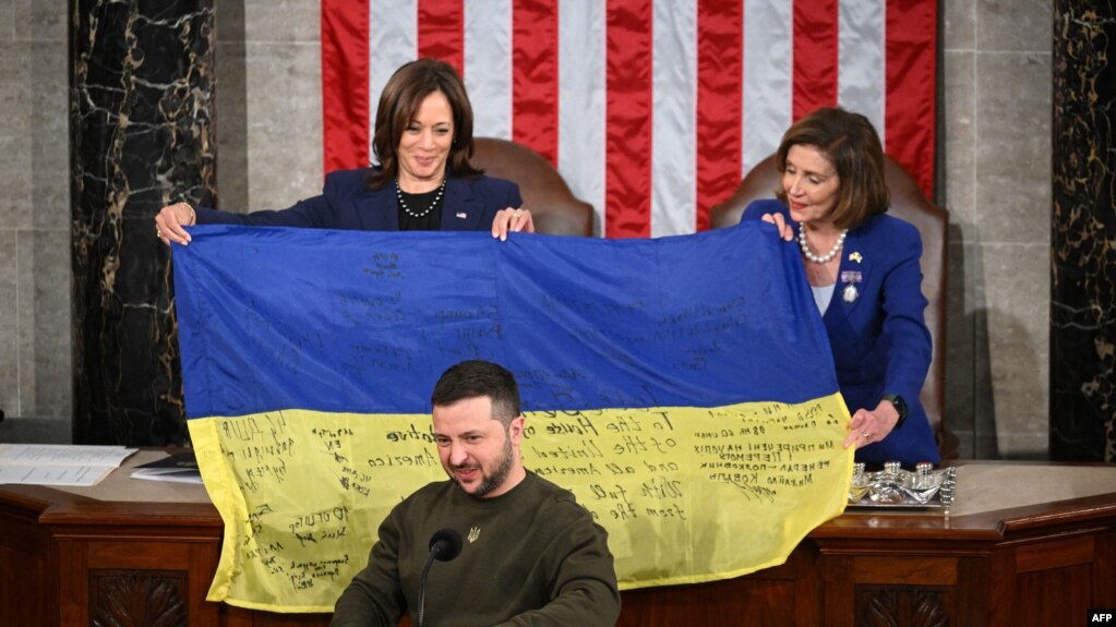 在乌克兰总统泽连斯基对国会联席会议发表演说之际，美国副总统哈里斯和众议院议长佩洛西展示着泽连斯基送给国会的有前线乌军签名的乌克兰旗帜。(2022年2月21日)(photo:VOA)