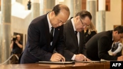 FILE - China's ambassador to Australia Xiao Qian writes a note while attending the national memorial service of Britain's Queen Elizabeth II in the Great Hall of Parliament House in Canberra on Sept. 22, 2022.