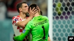 Borna Barisic, left, congratulates his teammate and goalkeeper Dominik Livakovic after Croatia defeated Japan on penalty kicks during the World Cup round of 16 soccer match at the Al Janoub Stadium in Al Wakrah, Qatar, Dec. 5, 2022. 