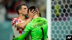Borna Barisic, left, congratulates his teammate and goalkeeper Dominik Livakovic after Croatia defeated Japan on penalty kicks during the World Cup round of 16 soccer match at the Al Janoub Stadium in Al Wakrah, Qatar, Dec. 5, 2022. 