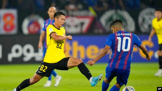 FILE - Huang Kaizho of Guangzhou Evergrande, left, fights for the ball against Leandro Velazquez of Johor Darul Ta'zim during a soccer match at Sultan Ibrahim Stadium in Johor, Malaysia, on April 15, 2022.