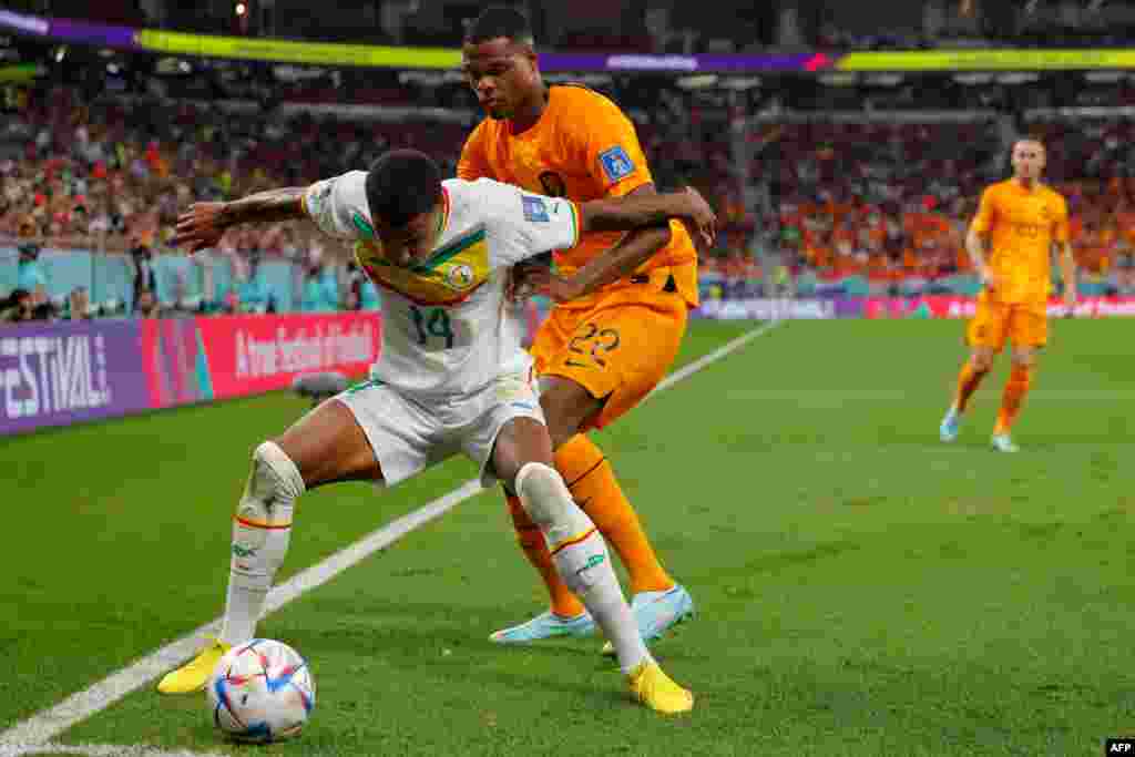 Mobatel to défenseur ya Sénégal Ismail Jakobs (G) na mobateli ya Netherland #22 Denzel Dumfries bazali kondongwana na match ya yambo ya groupe A ya mondial Qatar 2022 na stade Al-Thumama, Doha, 21 novembre 2022. (Photo Odd ANDERSEN / AFP)