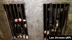 2010年7月7日韩国首尔举行的朝鲜战争展览会上一名韩国士兵(左)体验被关押在朝鲜牢房的感受