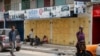 FILE - People sit in front of closed shops in the central business area of Accra, after shop owners in Ghana's capital closed their shops in protest of high costs, on Oct. 20, 2022.