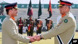 Panglima Angkatan Darat Pakistan Jenderal Qamar Javed Bajwa, kanan, menyerahkan tongkat komando kepada penggantinya Jenderal Asim Munir dalam upacara Pergantian Komando, di Rawalpindi, Pakistan, Selasa, 29 November 2022. (Foto: ISPR via AP)