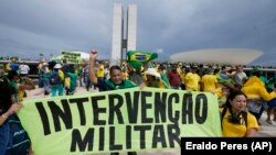 Manifestantes pró-Bolsonaro, seguram uma faixa que diz "Intervenção Militar" ao assaltarem o edifício do Congresso Nacional em Brasília, 8 Janeiro 2023