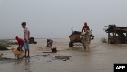 A resident rides on his cattle-pulled cart past a submerged bridge after a river overflowed due to heavy rains in Ilagan City, Isabela province, north of Manila, Jan 1, 2023.