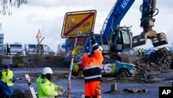 Workers from the German energy company RWE take down the place sign at the village Luetzerath near Erkelenz, Germany, Jan. 11, 2023.