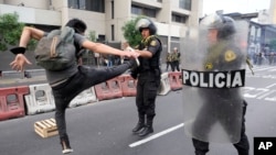 A supporter of ousted President Pedro Castillo jump kicks at a police officer during a protest in Lima, Peru, Dec. 8, 2022.