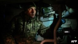 Un artillero ucraniano mira a través del periscopio de un obús autopropulsado hacia las posiciones rusas, en un campo cerca de una posición de primera línea no revelada en el este de Ucrania, el 30 de noviembre de 2022.