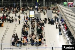 FILE - Tourists wait to check in for flights, at Bangkok’s Suvarnabhumi airport, Thailand, Jan. 4, 2023.