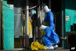 Trabajadores con equipo de protección se preparan para recolectar muestras de COVID de una mujer en su tienda cerrada en Beijing, el 1 de diciembre de 2022.