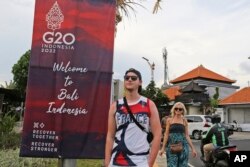 Turis berjalan melewati spanduk G20 di Nusa Dua, Bali, pada Jumat, 11 November 2022. (Foto: AP)