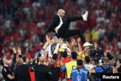 Morocco's players throw Coach Walid Regragui into the air after their victory over Canada that put them atop the Group F standings and into the knockout round of the World Cup at Thumama Stadium in Doha, Qatar, Dec. 1, 2022.