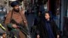 FILE - A Taliban fighter stands guard as a woman walks past in Kabul, Afghanistan, on Dec. 26, 2022. The Taliban has rejected a resolution by the U.N. Security Council condemning a ban on local women from working for the United Nations.