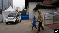 A woman and child wearing masks walk near a closed-off area in Beijing, Dec. 2, 2022.