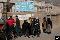 Afghan women students stand outside the Kabul University in Kabul, Afghanistan, Dec. 21, 2022. Taliban security forces in Kabul are upholding a higher education ban for women by blocking access to university campuses.