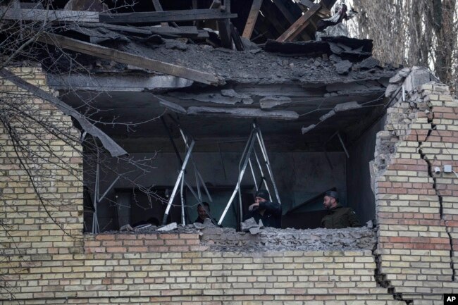 People check a tax office building that was heavily damaged in Russian shelling, in Kyiv, Ukraine, Wednesday, Dec. 14, 2022. (AP Photo/Evgeniy Maloletka)