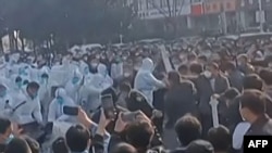 This image grab taken from AFP video footage and posted on Nov. 23, 2022 shows workers at Foxconn's iPhone factory in Zhengzhou in central China clashing with riot police as well as people wearing hazmat suits.