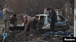 Investigators work near the bodies of local residents killed by shrapnel during Russia's missile attack in Zaporizhzhia, Ukraine, Dec. 5, 2022.