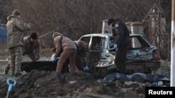 Investigators work near the bodies of local residents killed by shrapnel during Russia's missile attack in Zaporizhzhia, Ukraine, Dec. 5, 2022.