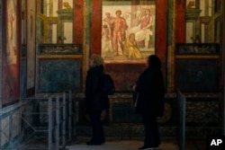 People admire frescoes in a "triclinium", or dining room, called " Hall of Ixium", part of the House of Vettii. (AP Photo/Andrew Medichini)