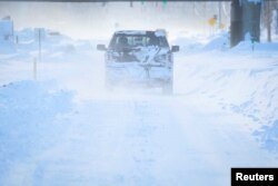 FILE = Vehicles drive through blowing snow following a winter storm that hit the Buffalo region on Main St. in Amherst, New York, Dec. 25, 2022.