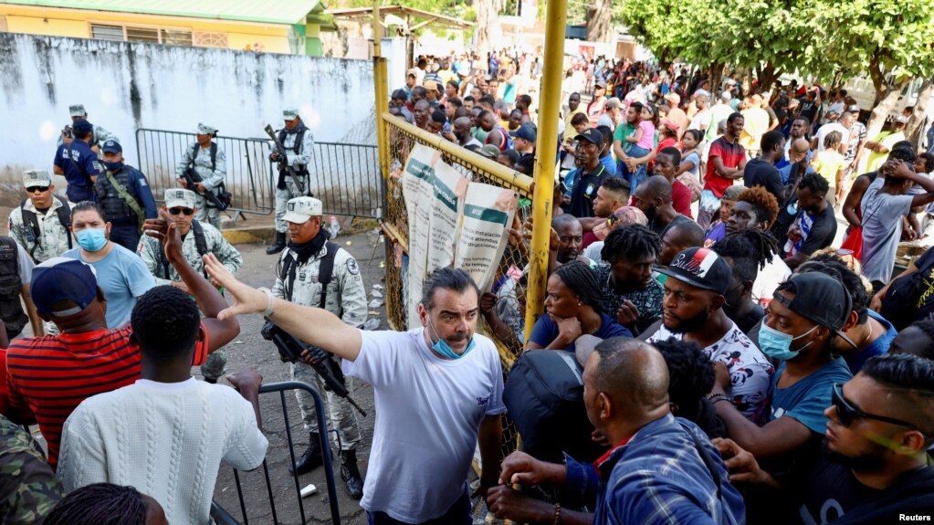 A worker gestures as he talks to migrants who want to regularize their migratory situation outside Mexico's Commission for Refugee Assistance in Tapachula, Chiapas state, Mexico, Jan. 3, 2023.