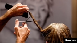 Penata rambut Belgia di salon rambut L'Atelier Chedly Boussigua, di Brussel, Belgia, memotong rambut pelanggan, yang akan dikumpulkan oleh asosiasi Dung Dung yang mengubah rambut menjadi ubin untuk menyerap zat kimia pencemar dalam air, 4 November 2022. REUTERS/Yves Herman