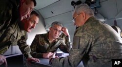 In this photo taken from handout video released by the Russian Defense Ministry's Press Service Dec. 18, 2022, Russian Defense Minister Sergei Shoigu, right, speaks to officers aboard a military helicopter at an undisclosed location in Ukraine.