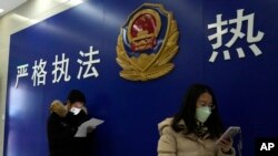 Warga antre di kantor polisi komunitas untuk mengajukan permohonan dokumen termasuk untuk paspor di dekat tulisan "Penegakan hukum yang ketat, pelayanan yang antusias" di Beijing, Rabu, 28 Desember 2022. ( AP/Ng Han Guan)