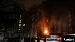 Жители Киева наблюдают за пожаром после обстрела города российскими беспилотниками-камикадзе 19 декабря 2022
