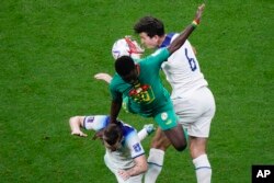 Britanik Harry Maguire (a dwat) ak Senegale Bamba Dieng goumen pou kontwol balon an nan Mondyal Foutbol Qatar la, 4 Desanm 2022.