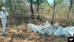 FILE - Forensic investigators remove bodies, Oct. 21, 2022 in the Mzimba District of Malawi where officials exhumed the bodies of 26 suspected Ethiopian migrants from a mass grave.