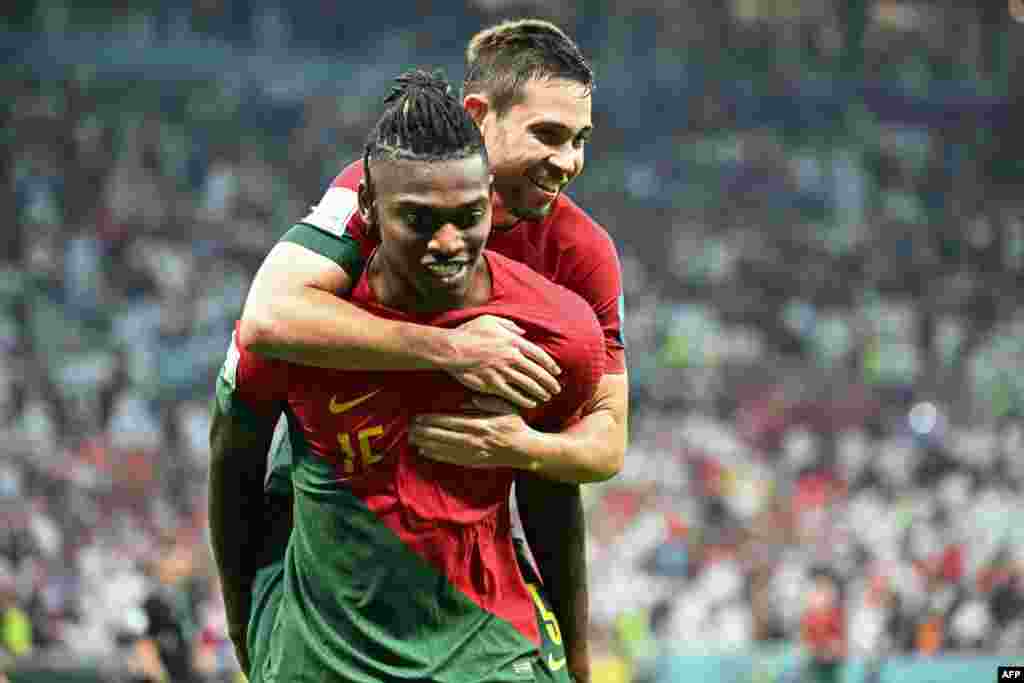 Attaquant ya Portugal #15 Rafael Leao amemi défesneur ya ekipi na ye #05 Raphael Guerreiro na mokongo na esengo na match na Suisse na stade Lusail, Doha, 6 décembre 2022. (Photo by Jewel SAMAD / AFP)