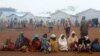 FILE - Families, who fled from the Democratic Republic of Congo, sit in a queue at refugee settlement camp in Kyangwali, Uganda, March 19, 2018. 