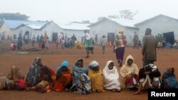 FILE - Families, who fled from the Democratic Republic of Congo, sit in a queue at refugee settlement camp in Kyangwali, Uganda, March 19, 2018. 