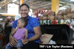Sofia Talei carries her child in front of her market stall as she poses for a photo for the Thomson Reuters Foundation in Fiji's capital Suva, Dec. 8, 2017.
