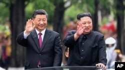 FILE - In this photo released by China's Xinhua News Agency, visiting Chinese President Xi Jinping, left, and North Korean leader Kim Jong Un wave from an open top limousine as they travel along a street in Pyongyang, North Korea, on June 20, 2019. 