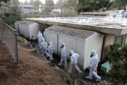 Workers from a Servpro disaster recovery team wearing protective suits and respirators enter the Life Care Center in Kirkland, Wash., to begin cleaning and disinfecting the facility, near Seattle, March 11, 2020.