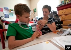 Rachel Scott, right, helps suction the mouth of her son, Braden, in Tomball, Texas, March 29, 2019.