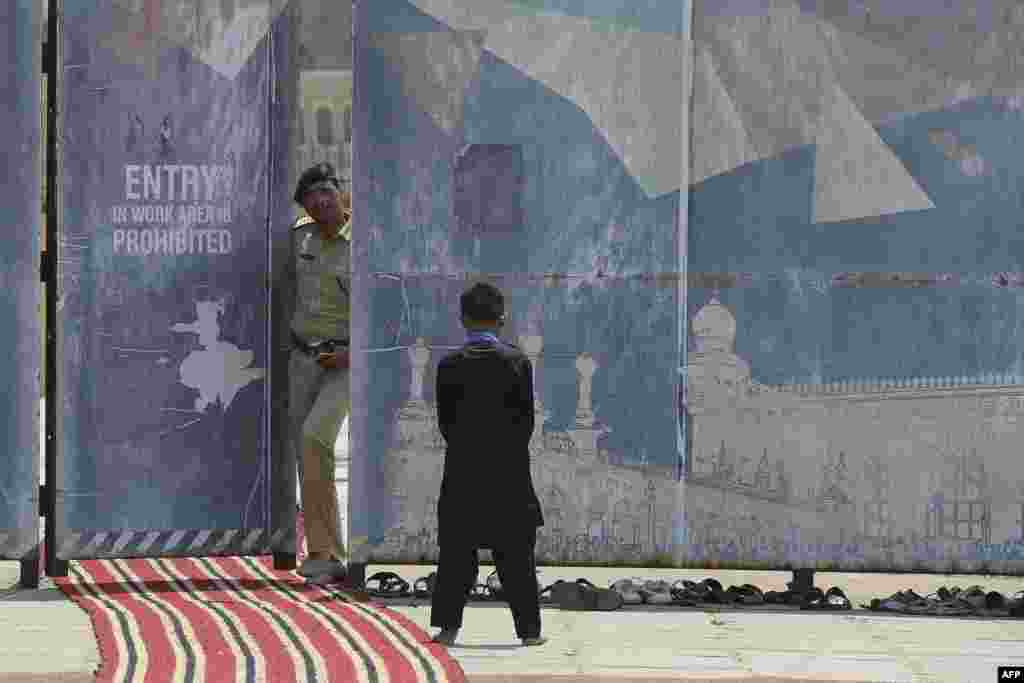 A police officer looks on as a Muslim boy offers Friday prayers at the Mecca Masjid in Hyderabad, India.&nbsp;(Photo by NOAH SEELAM / AFP)