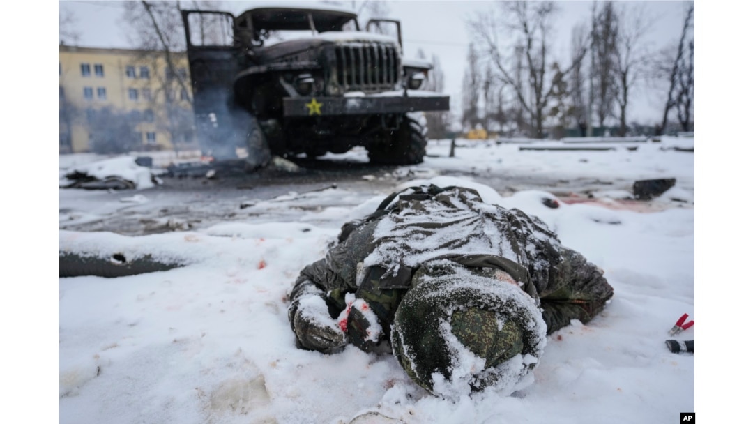 FILE - The body of a serviceman is coated in snow next to a destroyed Russian military multiple rocket launcher vehicle on the outskirts of Kharkiv, Ukraine, on Feb. 25, 2022.