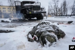 FILE - The body of a serviceman is coated in snow next to a destroyed Russian military multiple rocket launcher vehicle on the outskirts of Kharkiv, Ukraine, on Feb. 25, 2022.