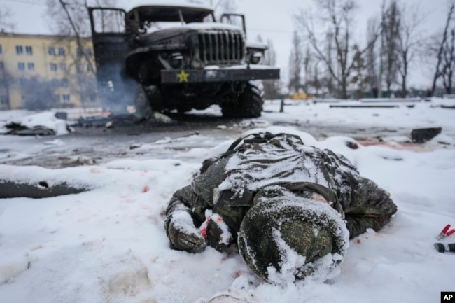 25 Şubat 2022 - Bir askerin cesedi, Ukrayna'nın Harkiv kentinin eteklerinde tahrip olmuş bir Rus askeri çoklu roketatar aracının yanında.