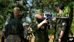 A Russian Army soldier looks through a sniper rifle scope as she and other soldiers guard a group of foreign journalists visiting a captured Ukrainian checkpoint and well-fortified trenches near Schastia town, on the territory which is under the Government of the Luhansk People's Republic control, eastern Ukraine, June 11, 2022.