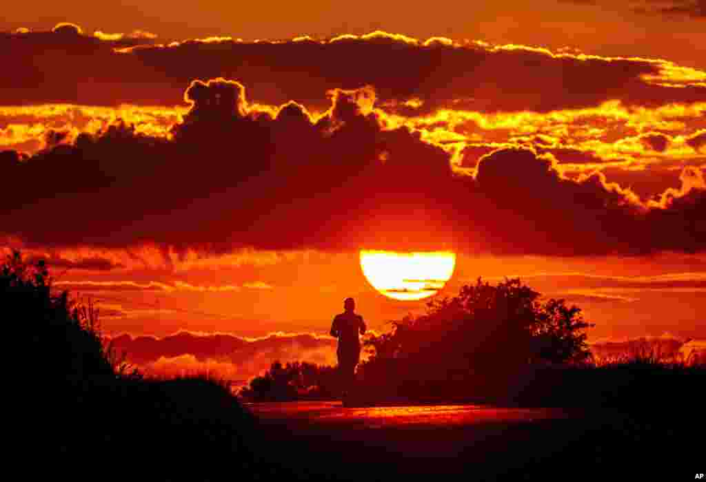 A man runs along a road as the sun rises on the outskirts of Frankfurt, Germany.